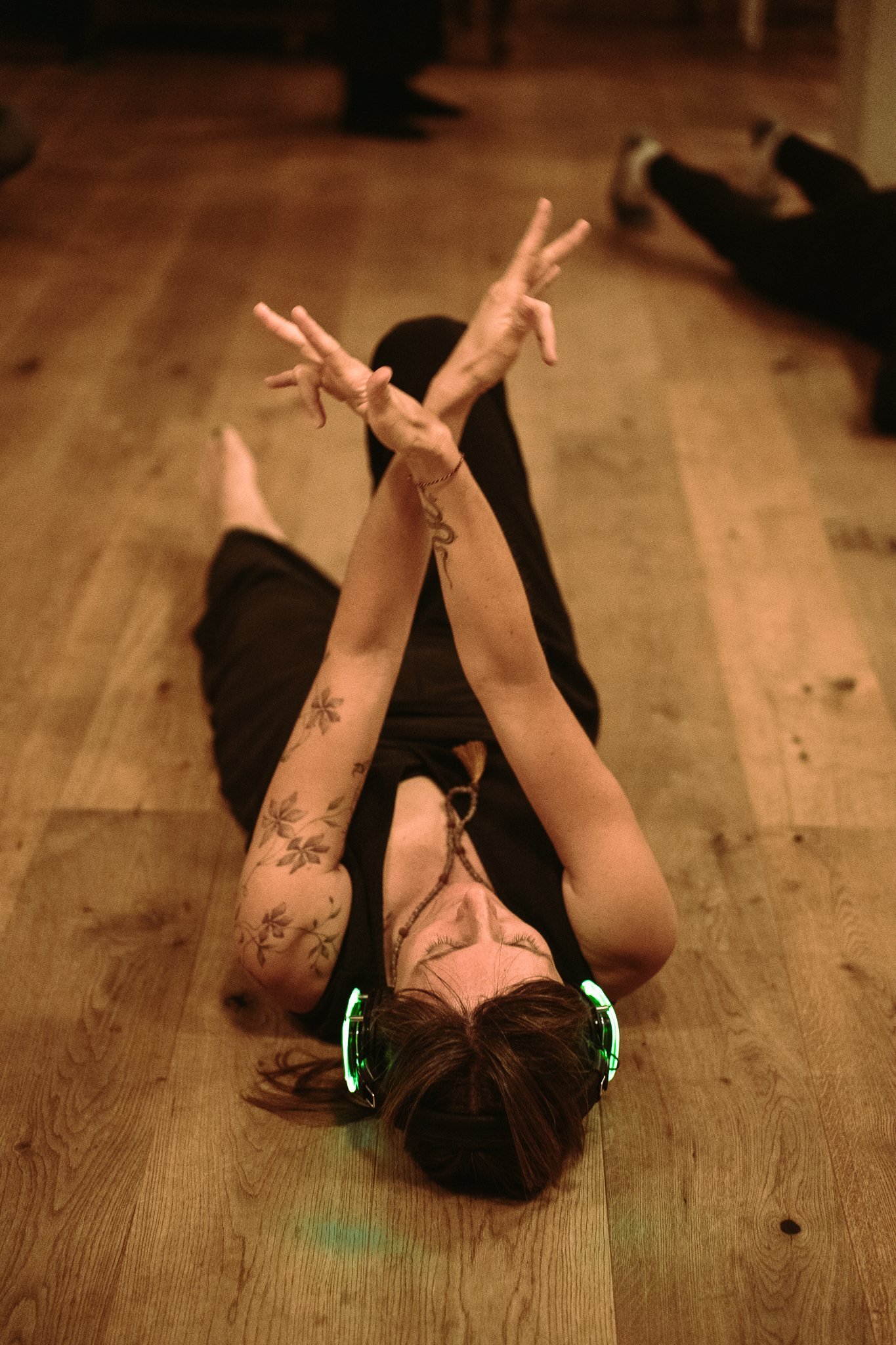 A dancer resting on the floor, arms crossed overhead in stillness
