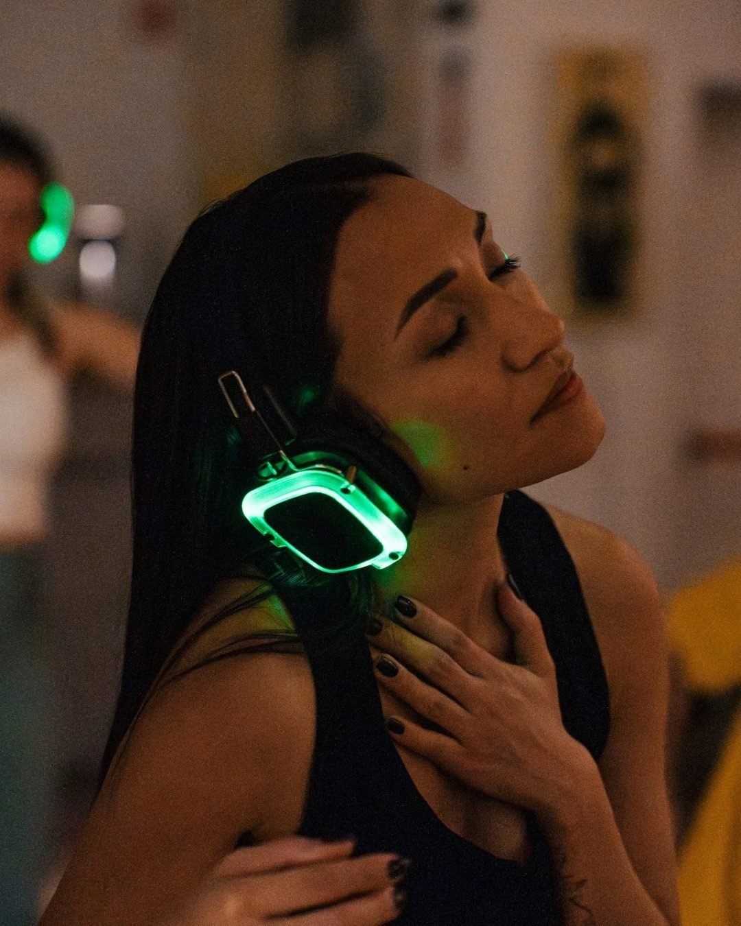 Close portrait of a dancer, eyes closed, headphone glow at the chest